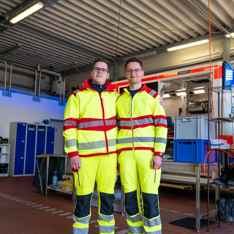 Zwei Männer die vor einem Rettungswagen stehen.